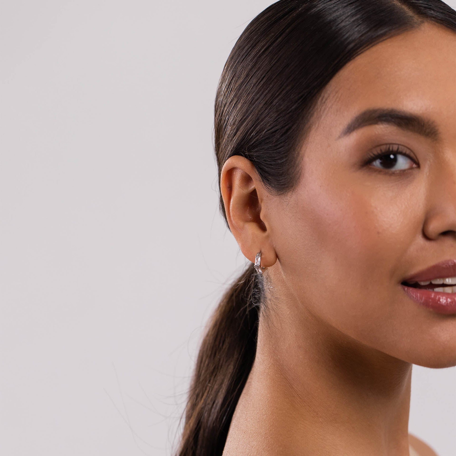 Elegante, silberne Ohrringe mit funkelndem Design, getragen von einer Frau, PURELEI.