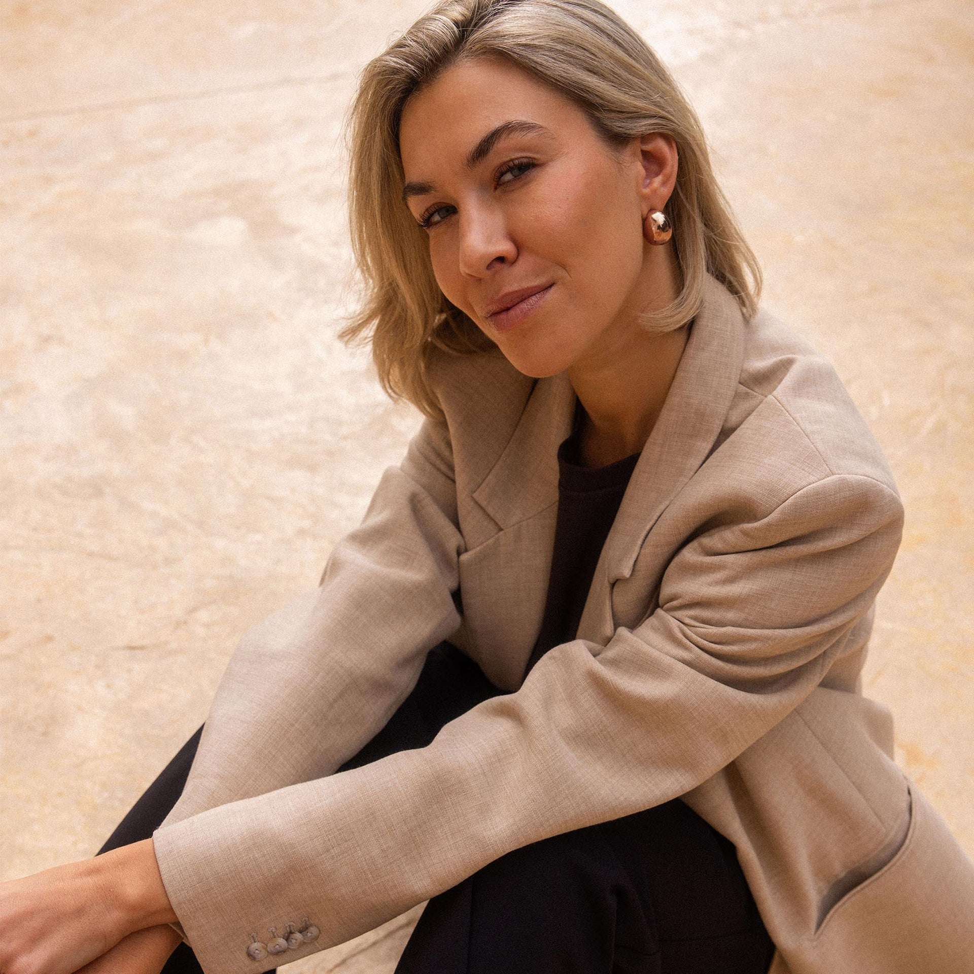 Elegante Ohrringe aus Gold, getragen von einer Frau in beigem Blazer, PURELEI.