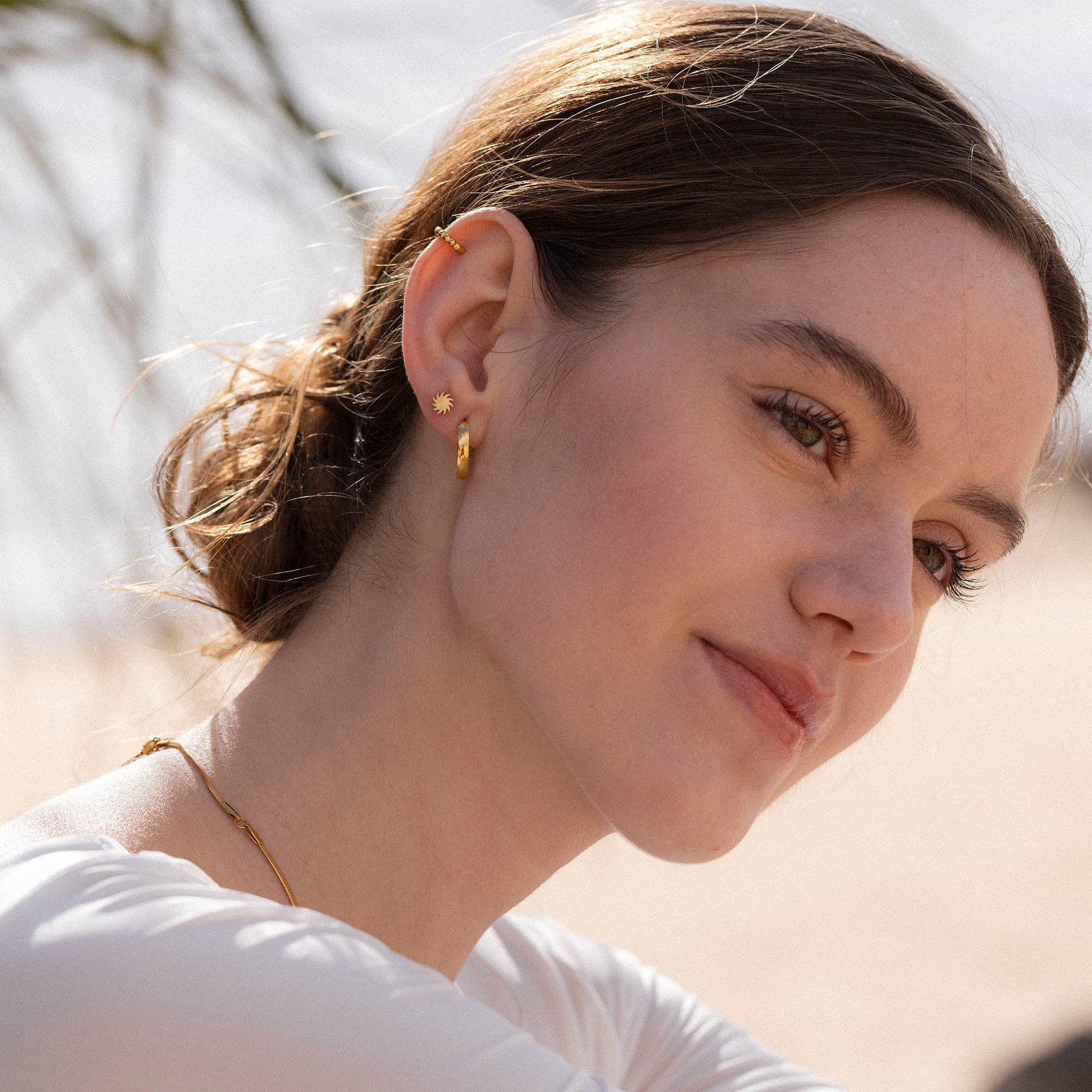 Zarte, roségoldene Ohrringe mit Sonnenmotiv, getragen von einer Frau, PURELEI.