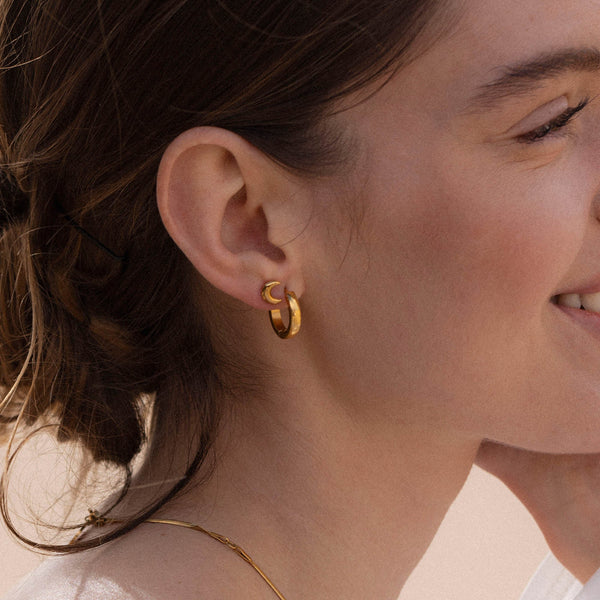 Roségoldene Creolen mit elegantem Design, getragen von einer lächelnden Frau – PURELEI.