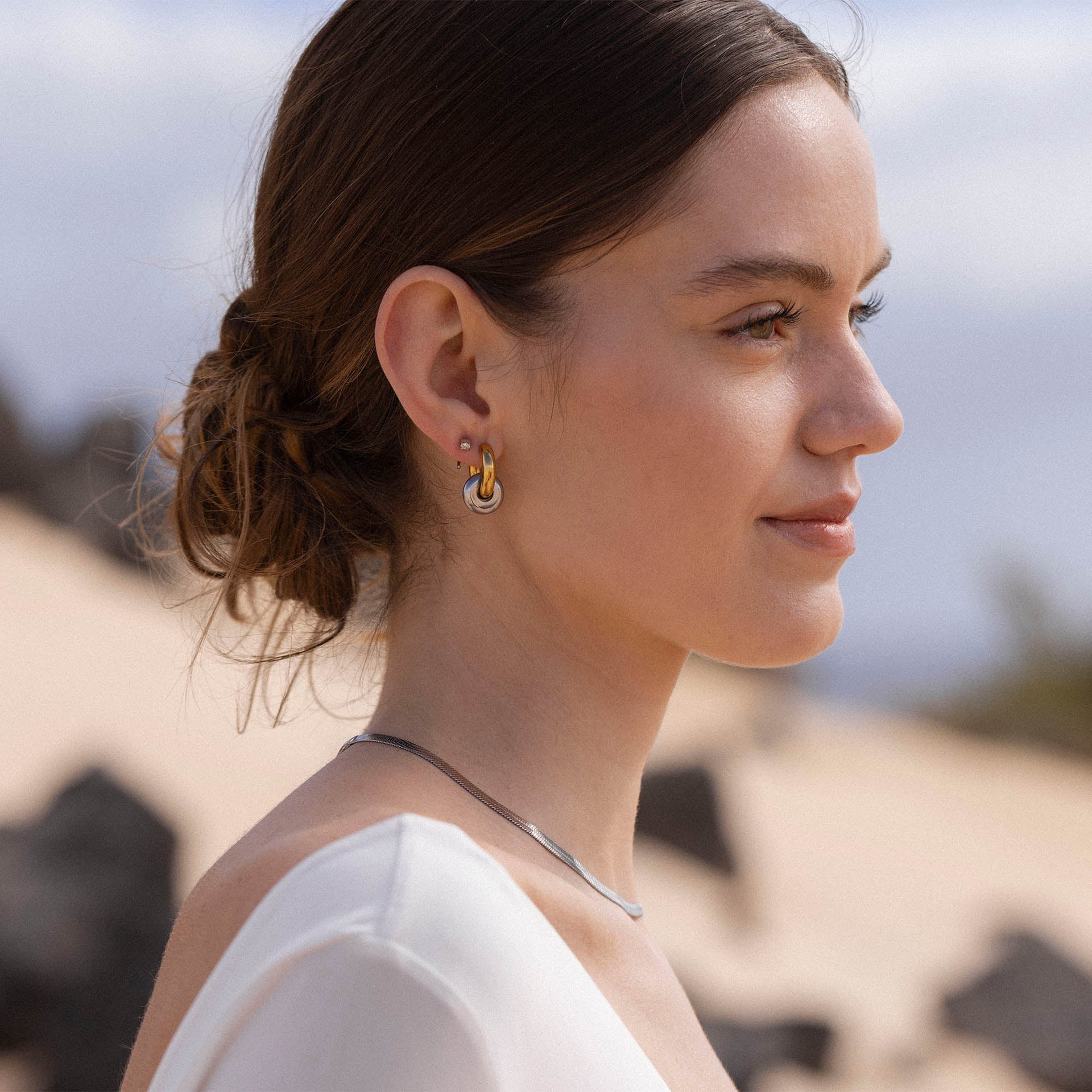 Silberne Creolen und zarte Kette von PURELEI, elegant und modern, getragen im Sonnenlicht.