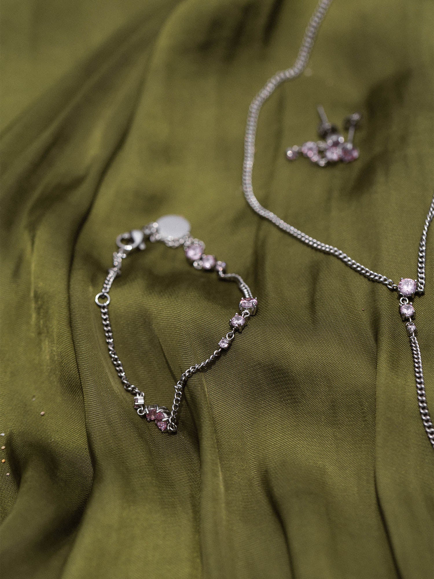 Silberne Kette und Armband auf grünem Stoff, PURELEI inspiriert von Eleganz und Feminität.