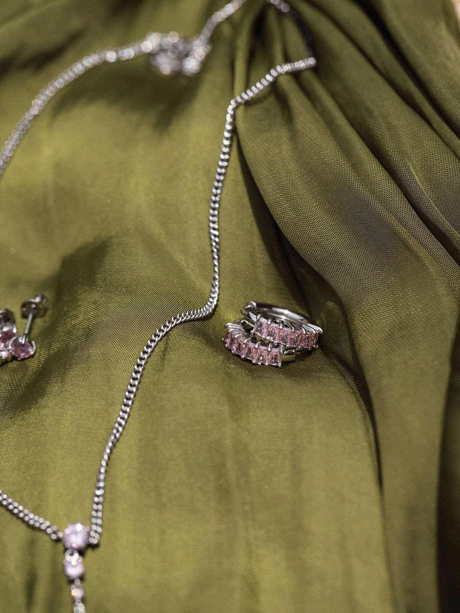 Silberne Kette und Ring auf grünem Stoff, elegant und modern, PURELEI.