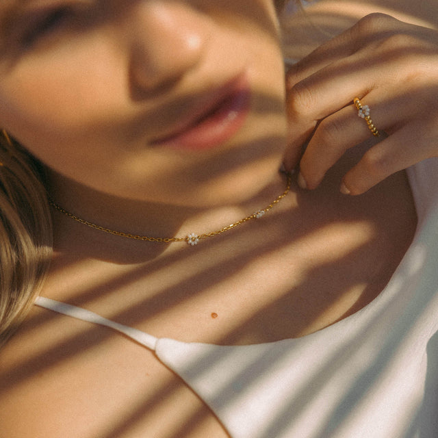 Roségoldene Kette mit blütenförmigen Details, getragen in warmem Licht – PURELEI.