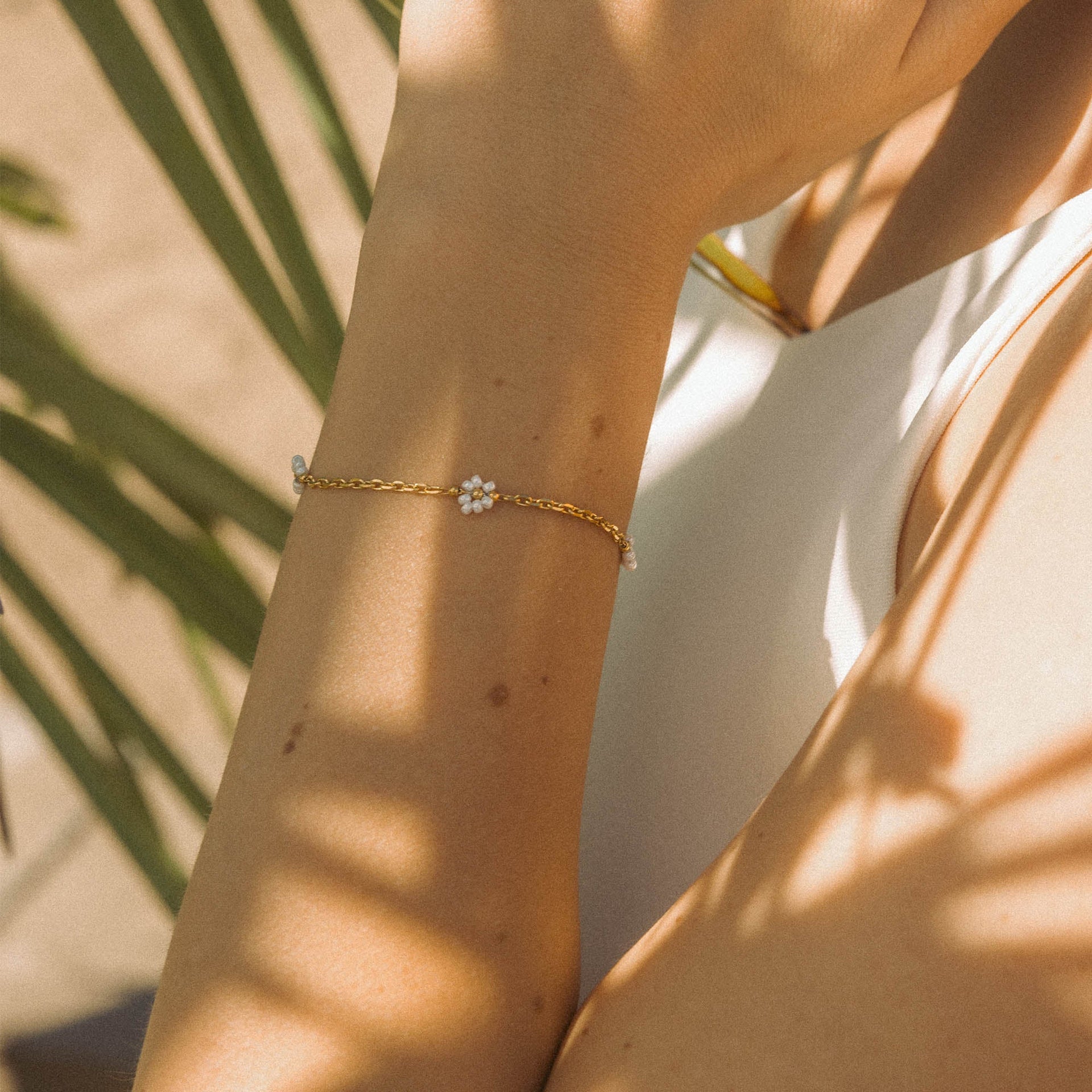 Roségoldenes Armband mit blütenförmigem Design, getragen im warmen Sonnenlicht – PURELEI.