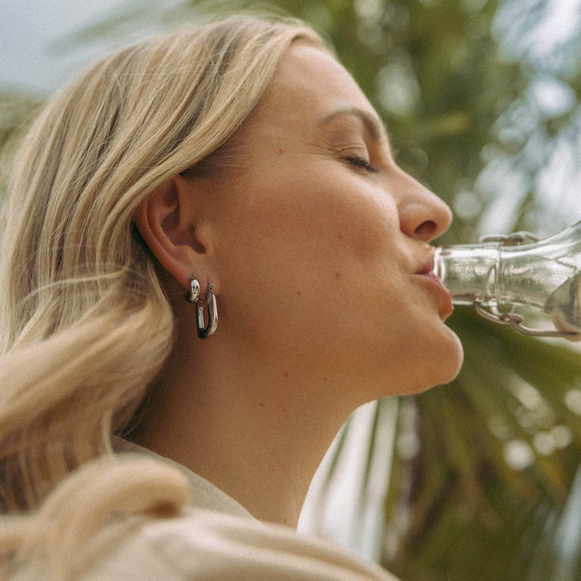 Silberne Creolen von PURELEI, elegant und modern, umgeben von tropischer Atmosphäre.