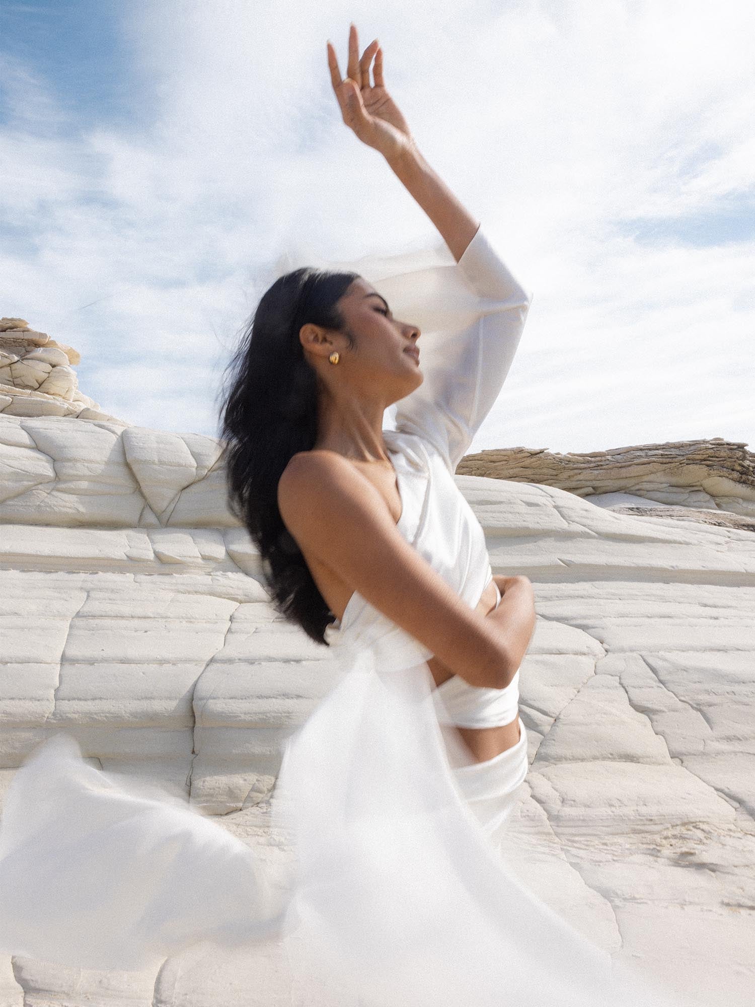 Moderne PURELEI Aquarius Letter Charm in 18K Gold, elegant getragen vor hellem Stein, naturverbunden und feminin.