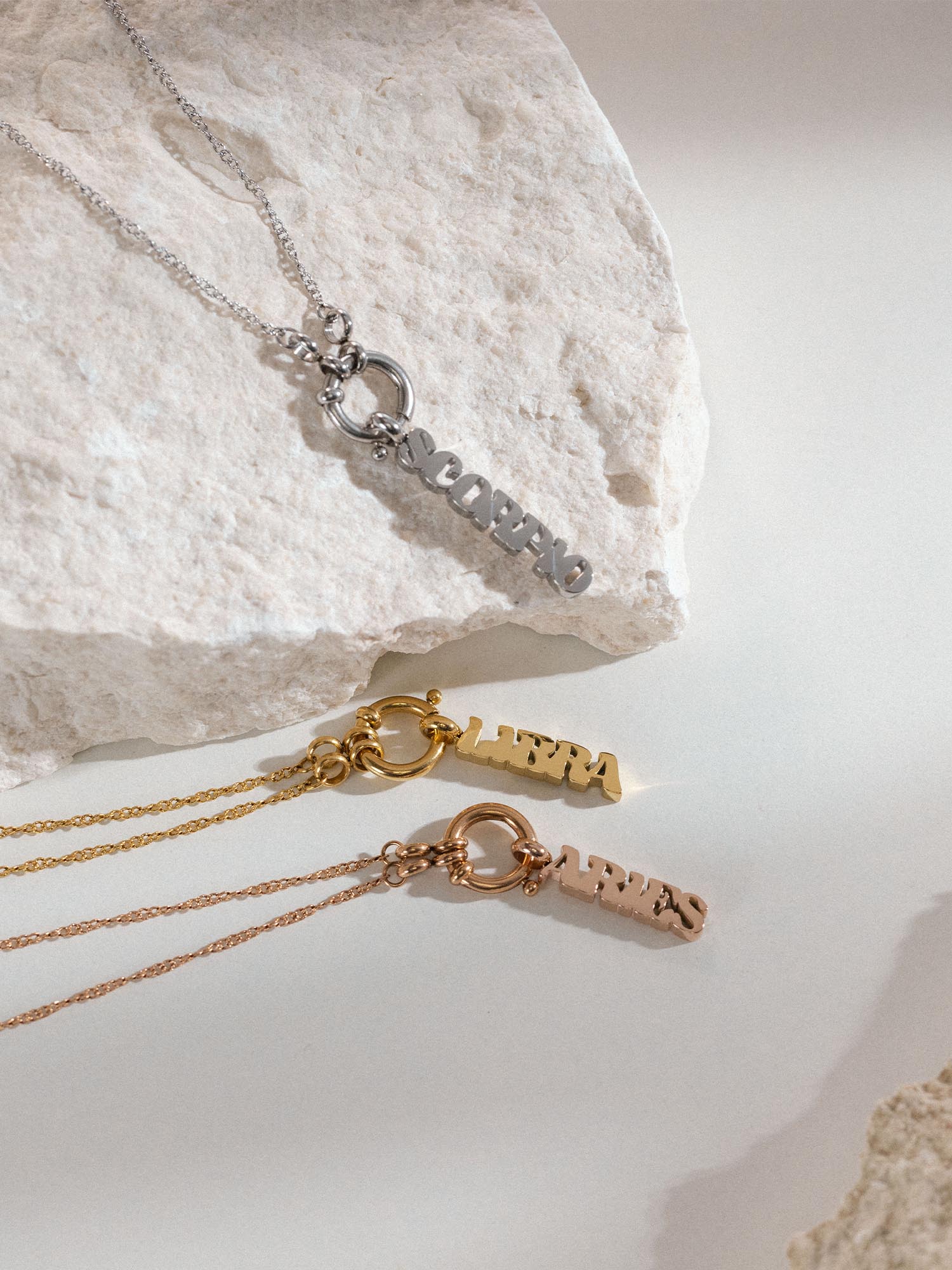Libra Letter Charm in Gold, Silber und Roségold aus nickelfreiem Edelstahl auf hellem Stein – PURELEI Eleganz.