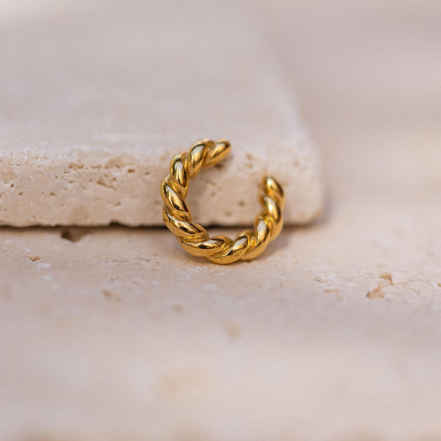 Goldene, gewundene Creole auf hellem Stein, inspiriert von PURELEI.