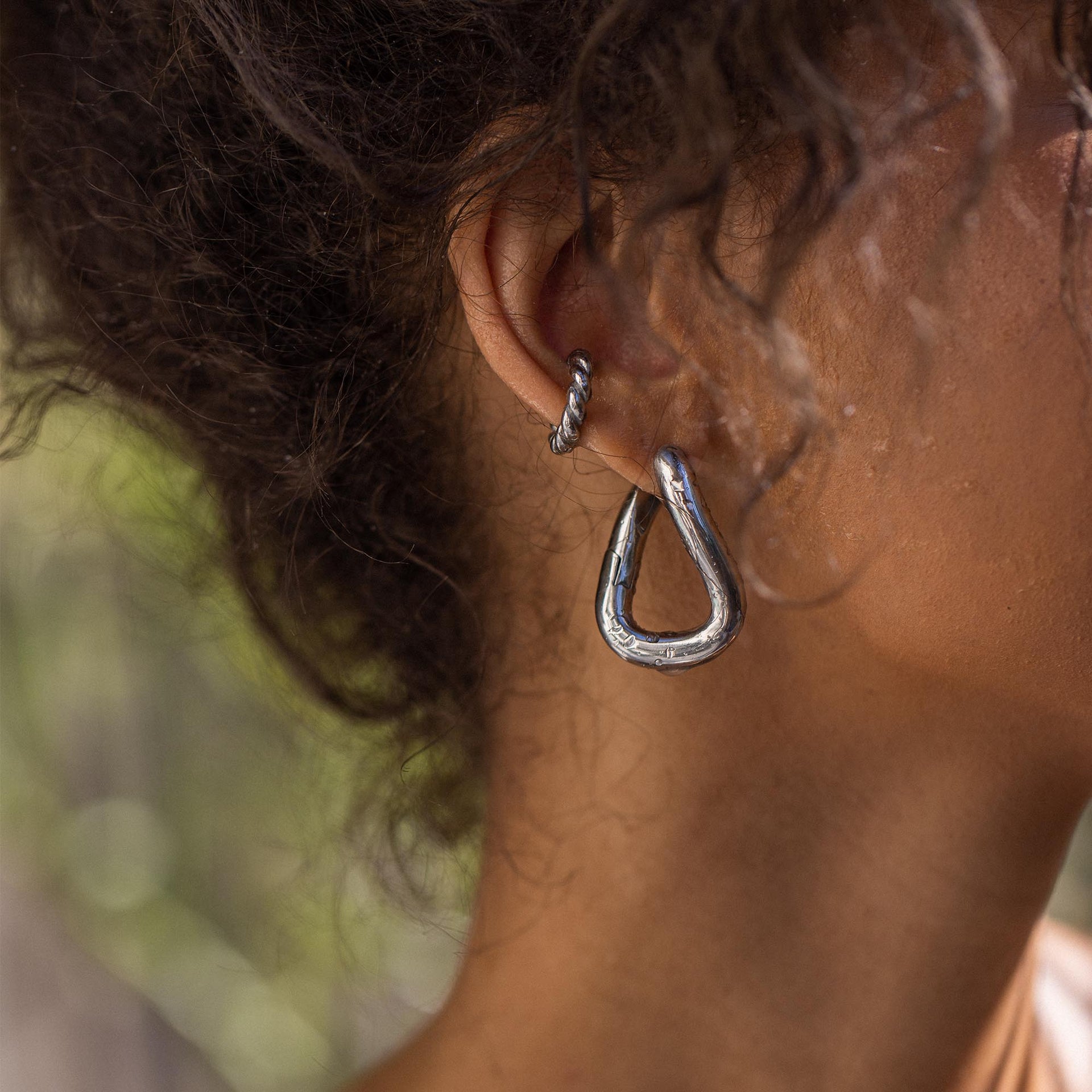Silberne, tropfenförmige Ohrringe von PURELEI, elegant und modern, getragen in natürlicher Umgebung.