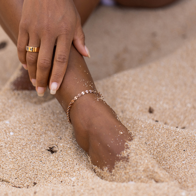 Zartes, roségoldenes Armband am Handgelenk, umgeben von Sand – PURELEI.