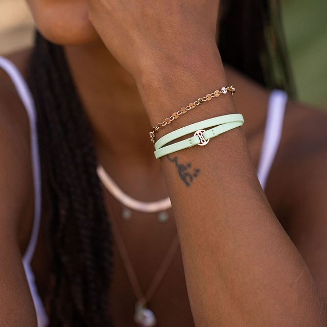 Weißes Armband mit goldener Schnalle, getragen am Handgelenk, PURELEI Stil.