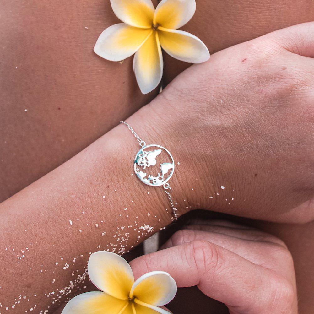 PURELEI World Map Armband aus nickelfreiem Silber, zart am Handgelenk mit tropischem Blumenakzent getragen