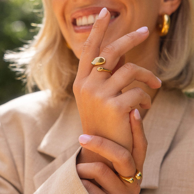 Goldene Ringe mit organischen Formen, getragen von einer lächelnden Frau, PURELEI.