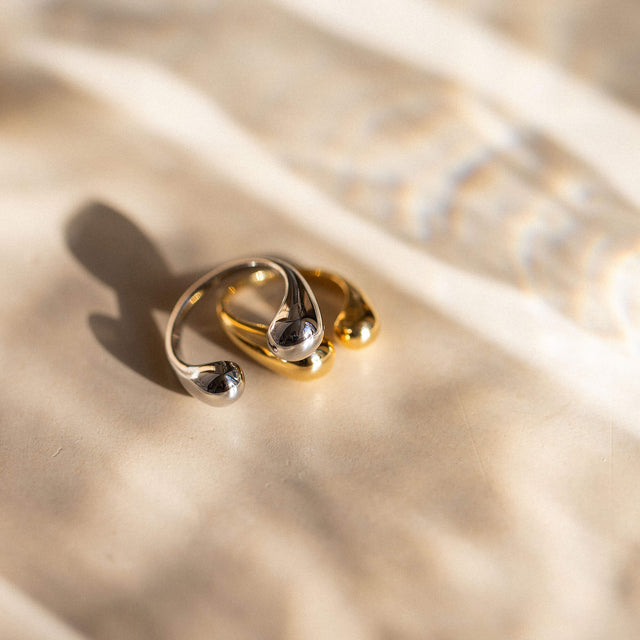 Silberne Ringe von PURELEI auf sanftem Stoff, elegant und modern in warmem Licht.