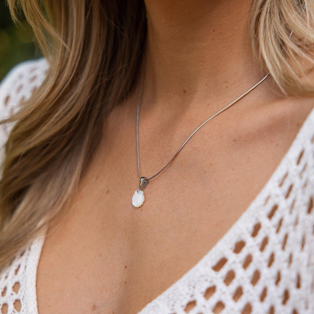 Silberne Kette mit Muschel-Anhänger, getragen in tropischer Eleganz von PURELEI.
