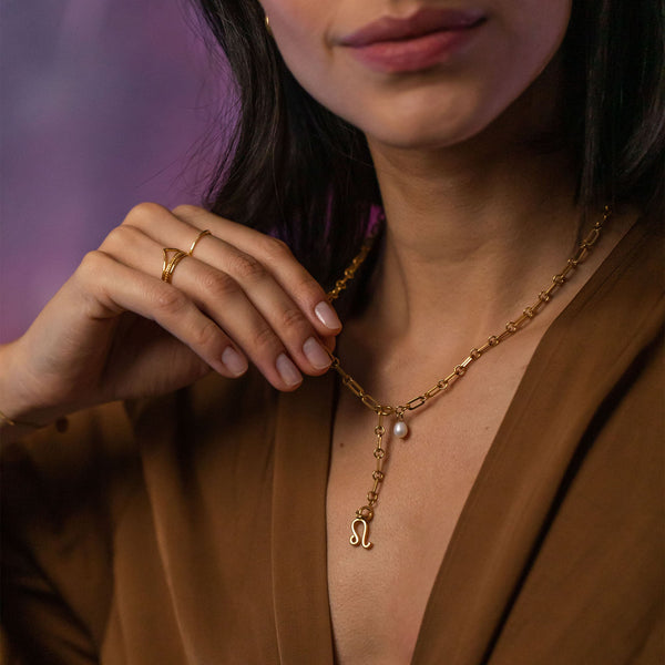 Löwe Zodiac Charm von PURELEI in 18K Gold mit zartem Sternzeichen-Anhänger und Perle, elegant am Hals getragen.